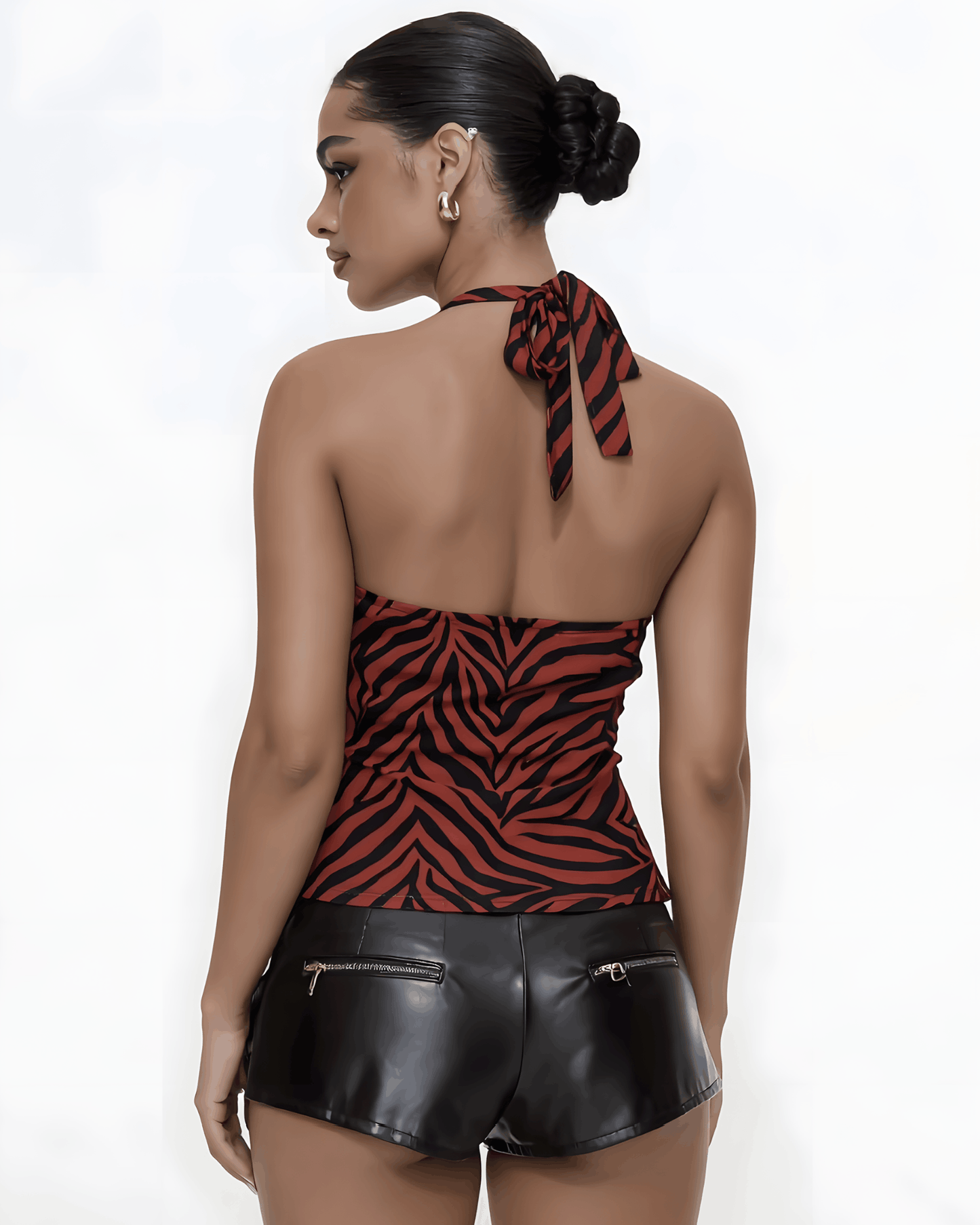 Side profile of a model wearing a red and black zebra patterned halter top and black PU leather cargo shorts with side pockets
